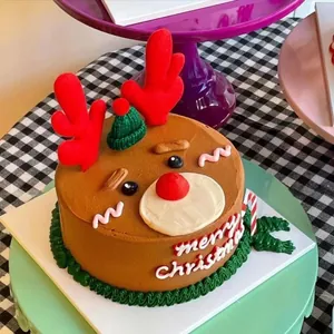 Close-up of reindeer Christmas cake with plush antlers and a mini green knitted hat