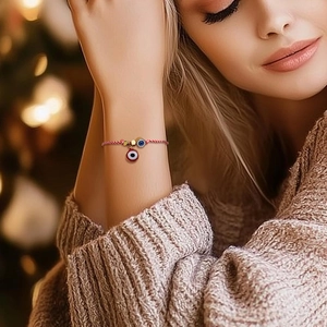 Detail of red and white woven evil eye bracelet on wrist with warm holiday background