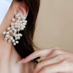 Gros plan de boucles d'oreilles perles et pampilles dorées portées par un mannequin