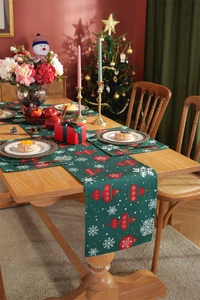 Close-up of green festive table runner and placemats with red Christmas ornaments on wood