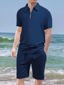 Detail of dark blue waffle textured polo shirt and shorts set on a beach background