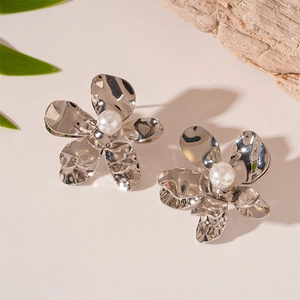 Detail of silver metallic flower earring with liquid texture and a white pearl center