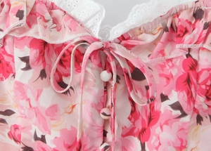 Close-up of pink floral dress featuring white lace trim and delicate fabric covered buttons