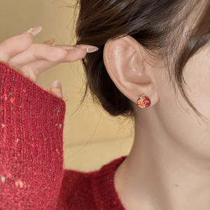 Detail view of red pomegranate earrings with sparkling zircon inlay on woman ear