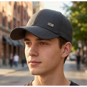 Close-up of charcoal grey baseball cap with metallic logo tag worn in an urban setting