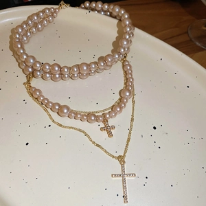Detail of champagne pearl necklace with double cross pendants on ceramic plate