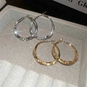 Macro view of twisted hoop earrings with sparkling pavé crystals in gold and silver