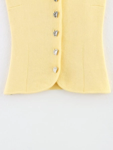 Gros plan d'un débardeur en maille jaune avec boutons métalliques et ourlet incurvé