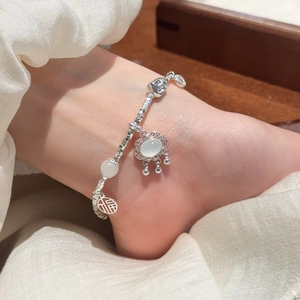 Detail view of a silver box chain bracelet with Fu character and white stone charms
