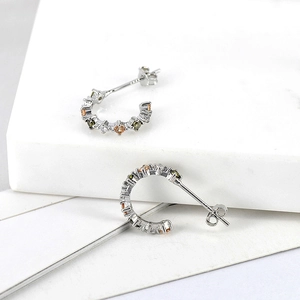 Detailed view of S925 silver C-shaped earrings with colorful zircon stones on marble