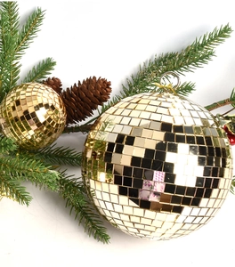 Macro shot of two golden disco mirror balls with silver hanging rings and pine tree decor