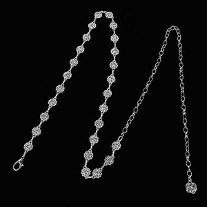 Detail of silver clover-shaped metal chain belt with lobster clasp on black background