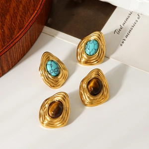 Macro view of vintage wavy gold-plated stud earrings with turquoise and tiger eye stones