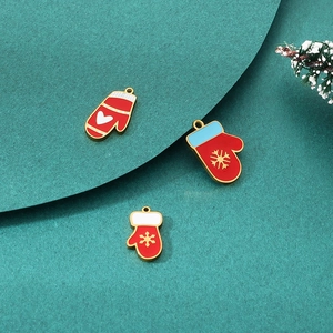 Detail of red enamel Christmas glove pendants with gold snowflakes on snowy pine background