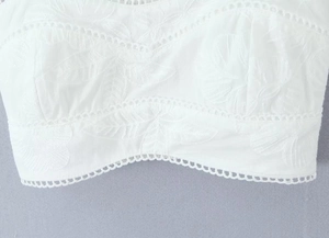 Gros plan détaillé de la broderie florale blanche et de la dentelle sur un débardeur