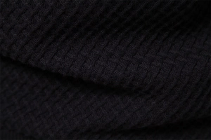 Macro detail of high-quality black waffle knit texture on this cotton sweater for men
