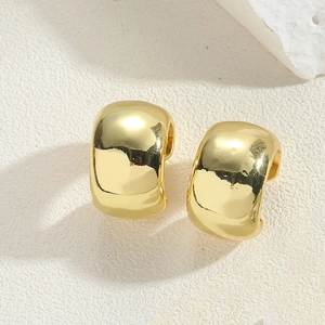 Detailed close-up of chunky gold layered ear cuffs on a minimalist white stone surface