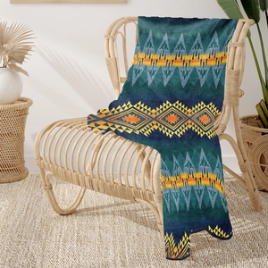 Bohemian geometric flannel blanket draped over a rattan chair in a cozy living room