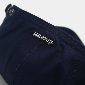 Detail of navy twill cotton beret with double stitching and since 1991 embroidery patch