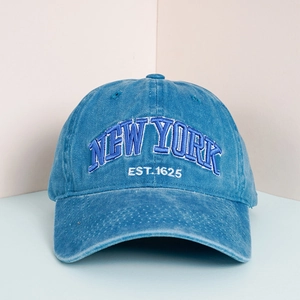 Close-up of New York Est. 1625 embroidery on washed blue cotton baseball cap texture