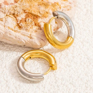 Detailed close-up of mixed metal gold and silver hoop earrings on natural stone