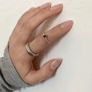 Detailed close-up of 925 sterling silver twill ring and black agate gemstone ring on finger