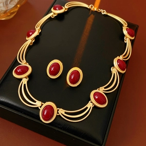 Detailed view of vintage gold necklace and oval red gemstone earrings set in a black box