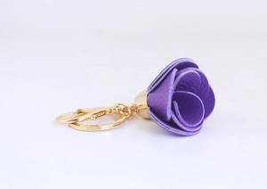 Gros plan d'un porte-clés rose en cuir violet avec crochet en métal doré sur blanc