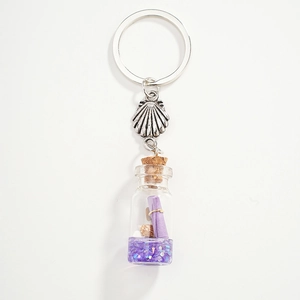 Detail of seashell keychain with glass bottle filled with purple glitter and tiny shells