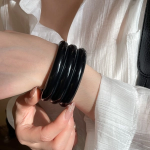 Detail shot of three layered black glossy resin cuff bracelets on a model's wrist