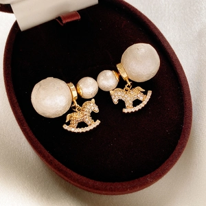 Close-up of rocking horse pearl earrings with pavé zircon stones in a velvet box