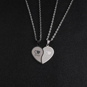 Gros plan de pendentifs en forme de cœur emboîtables en acier noir et argent avec gravures