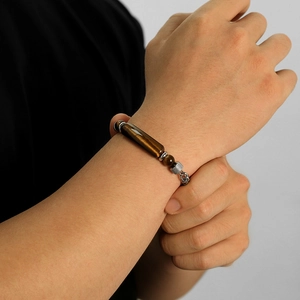 Detailed close-up of a men's stainless steel bracelet with tiger eye stones on a wrist