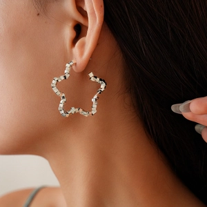 Detail of silver hollow star stud earring featuring a metallic faceted bead texture