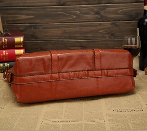 Dettaglio del fondo della borsa tote in pelle cerata marrone su sfondo di giornale vintage