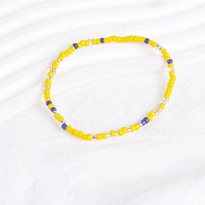 Close-up of bohemian stacked bracelet with vibrant yellow, blue, and gold beads