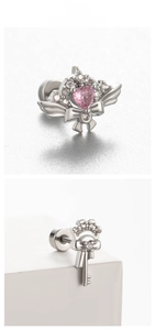 Dettaglio macro di orecchini ad ala d'angelo in argento con zircone rosa e design a chiave