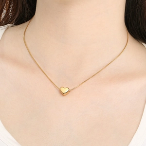 Collier minimaliste à pendentif cœur doré sur chaîne serpent porté par un mannequin