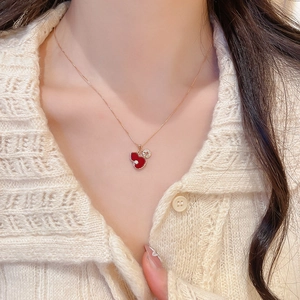 Close-up of a gold necklace featuring a red enamel gourd pendant and sparkling zircon stones