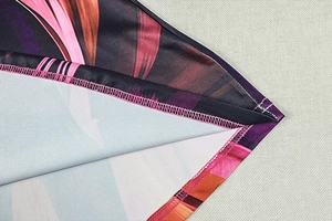 Detail view of colorful printed dress showing precision pink flatlock stitching and vibrant fabric
