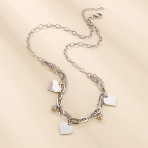 Detailed view of silver layered heart pendants and mixed chain texture on neutral background