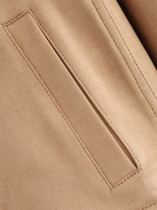 Detail of camel suede jacket showing precision stitching and fabric texture on pocket