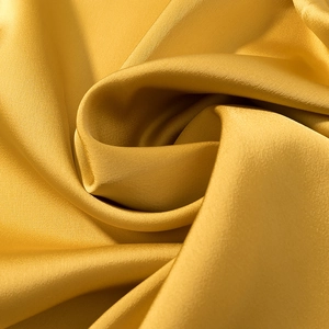 Close-up of golden satin fabric texture showing smooth surface and elegant silk draping