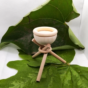 Macro detail of natural wooden essential oil diffuser bowl on tripod stand with green leaf