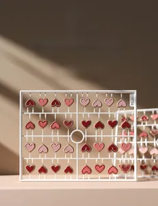 Macro detail of 3D embossed pink heart nail charms displayed on a professional white rack