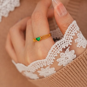 Détail d'une bague vintage plaquée or avec coeur vert et anneau au design ajouré