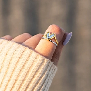 Minimalist gold and silver two-tone heart rings set worn on a finger with knitwear background