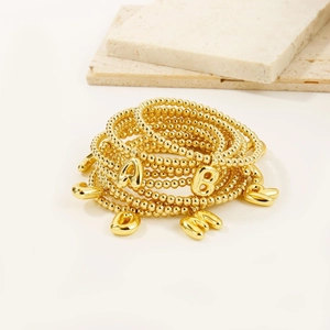 Detailed macro of 18k gold plated bead bracelets featuring puffy alphabet letter charms