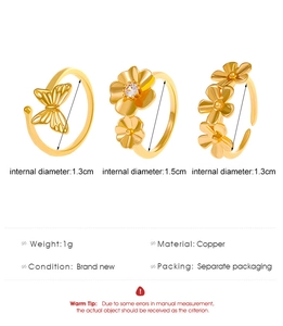 Detailed view of gold copper rings showing butterfly, floral, and rhinestone designs