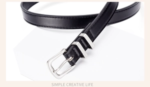 Close-up of black slim waist belt with silver pin buckle and fine stitching detail